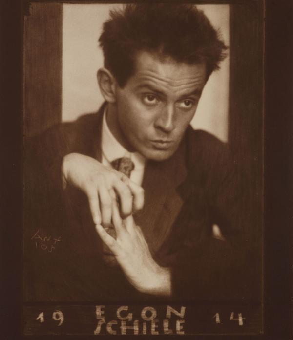 Egon Schiele mit verwobenen Fingern und gesenktem Blick 
